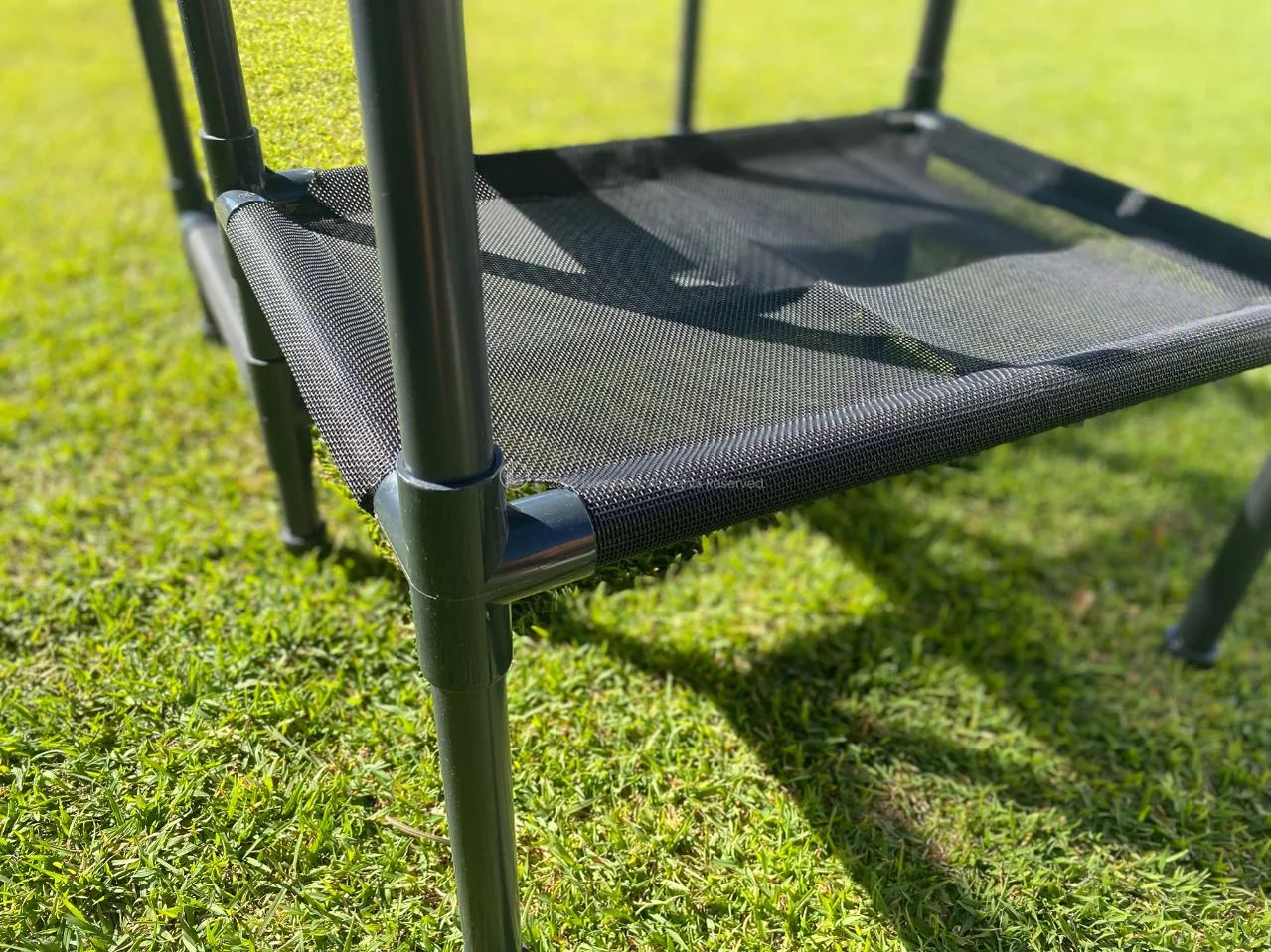 Cats climbing and lounging on multiple tiers of a LuxeyPets SkyRise outdoor cat tower in a garden setting