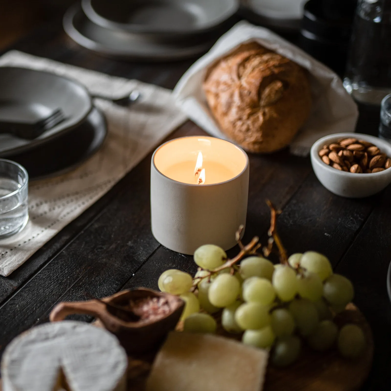 Thistle Farms candle burning on a side table in a living room, illustrating home fragrance use