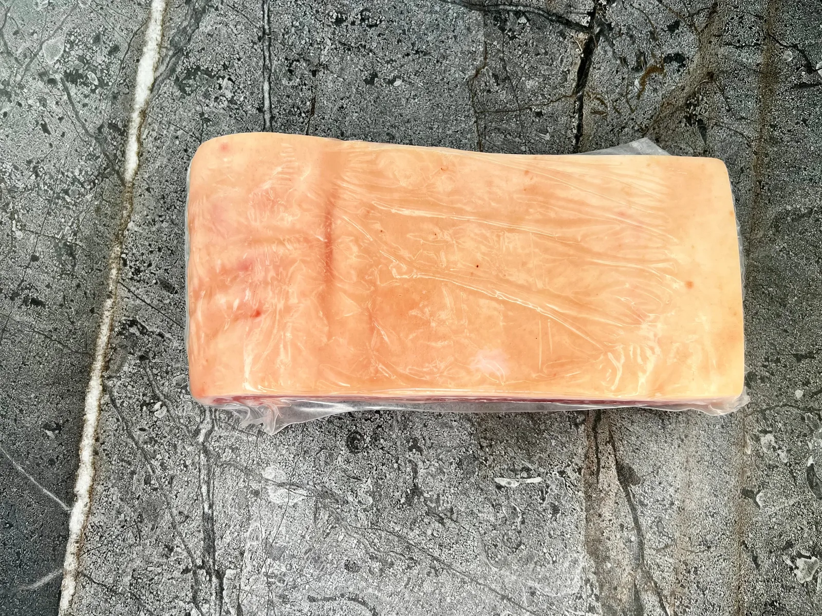 Cordobes Foods Pork Belly Skin-On Slab shown skin side up in its vacuum pack